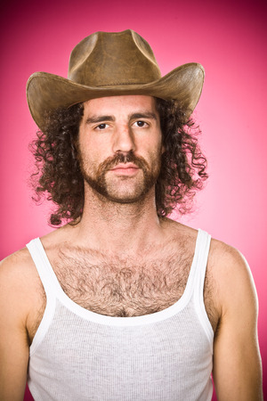 shabby cowboy with mustache and hat portrait isolated on pinkの写真素材