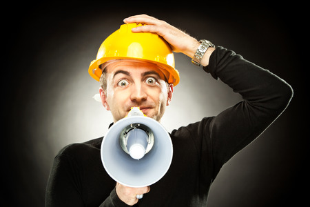 worker yell through the megaphone on black backgroundの写真素材