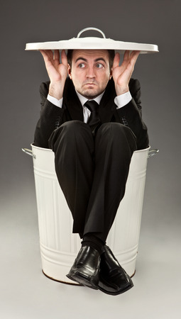 funny businessman throw out in a bin on grey backgroundの写真素材