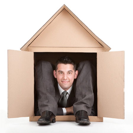 elegant smiling happy flexible contortion businessman in cardboard houseの写真素材