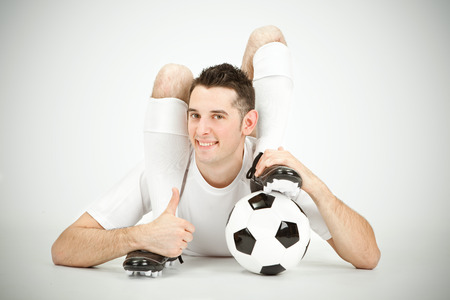 Contorsionist flexible soccer football player thumb up ball under foot on grey background