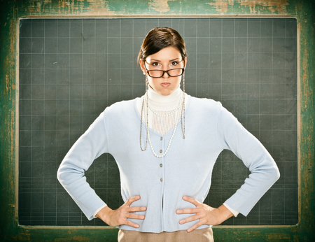Beautiful serious young teacher with glasses and blackbouardの写真素材