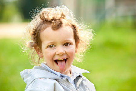 beautiful blond curly hair child play outdoor in a parkの写真素材