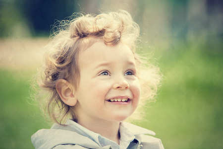 beautiful blond curly hair child play outdoor in a parkの写真素材