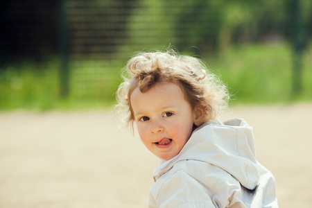beautiful blond curly hair child play outdoor in a parkの写真素材