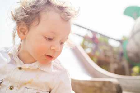 beautiful blond curly hair child play outdoor in a parkの写真素材