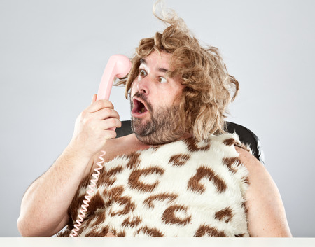 ugly rude prehistoric man talking on the phoneの写真素材