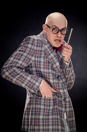 bald caucasian professor or teacher with bow and glasses tie point stick on blackboard with copy spaceの写真素材