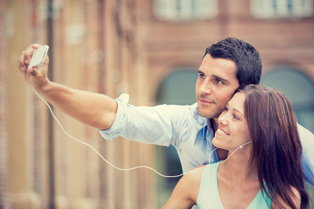 young brunette couple having fun together with music at parkの写真素材