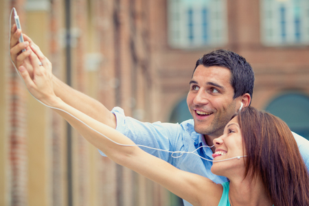 young brunette couple having fun together with smartphone at parkの写真素材
