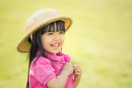 happy asian smiling child with hat play in a gardenの写真素材