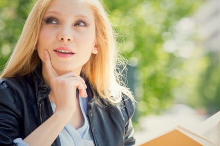 smiling blonde young woman read and study in a gardenの写真素材