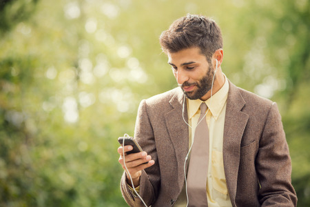 Young business man relaxing using smartphone outdoor in natureの写真素材