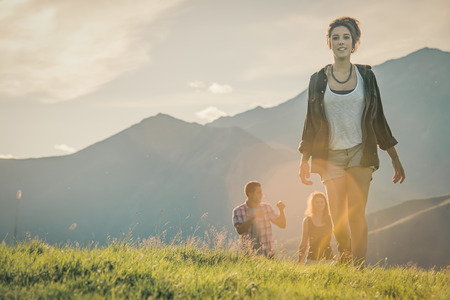 Three friends walk on mountain path in sunny dayの写真素材