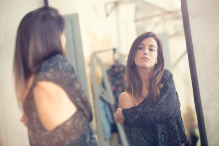 Young woman looking in the mirror portrait in a shopの写真素材
