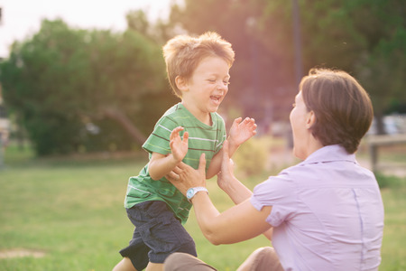happy smiling blond caucasian kid outdoor at park running and play with his mumの写真素材
