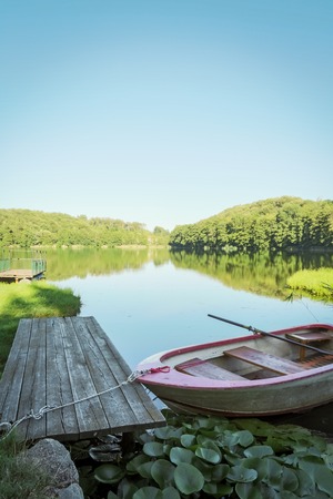 small boat in lake in mountain with green field and blue skyの写真素材