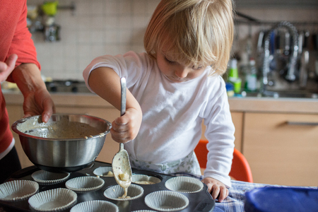 baby girl daughter help cooking with her mom in kitchenの写真素材