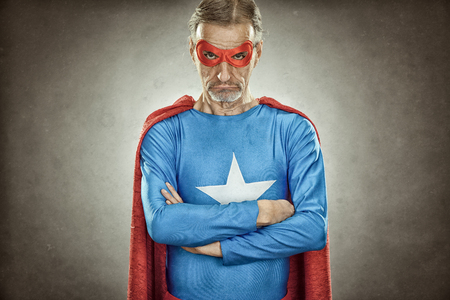 senior superhero man in blue costume red cloak and mask old portrait on textured backgroundの写真素材