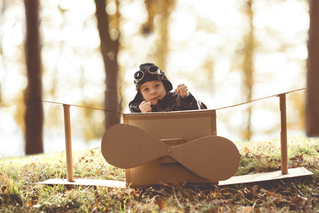 front view vintage pilot boy flight by imagination on cardboard plane outdoorの写真素材
