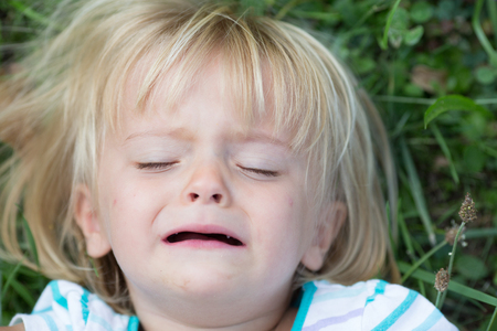 serious crying sad young baby caucasian blonde real people girl close portrait outdoorの写真素材
