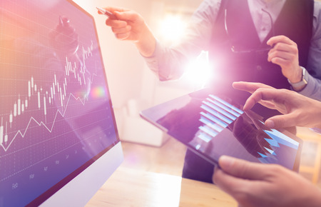 Two colleagues working on global financial trading strategy analysis using tablet and laptop.Modern business team innovation concept.Office project meeting with virtual forex graph and chart dataの写真素材