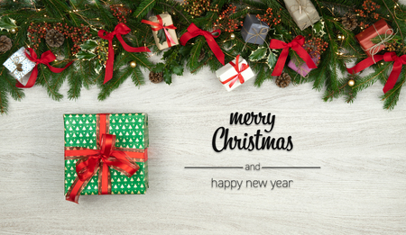 Merry Christmas and happy new year greetings in vertical top view white wood with pine branches,ribbons, lights and gift present box decorated frame.Xmas winter holiday season social media cardの写真素材