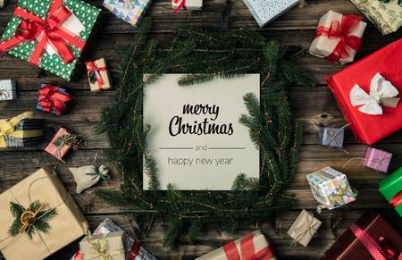 Merry Christmas and happy new year greetings in vertical top view vintage wood.Pine branches,ribbons, lights,gift present boxes decorated frame.Xmas winter holiday season social media card backgroundの写真素材