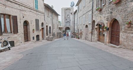 Romantic couple walking visiting rural town of Assisi.Back follow.Friends italian trip in Umbria.4k slow motionの写真素材