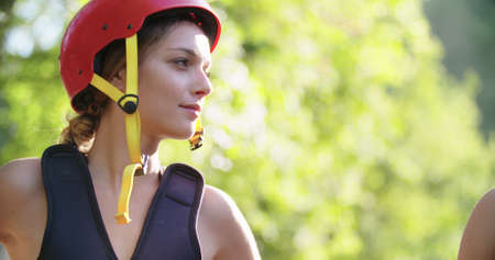woman wearing life jacket and sport helmet smiling before rafting river descent.Group of people briefing before starting extreme sport activity.Rafting extreme sport.Handheld.の写真素材
