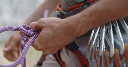 Climber man preparing for climbing up the rocky wall rift by checking rope. Climbing extreme active...