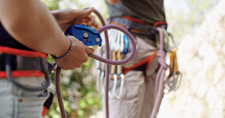 Climber man preparing for climbing up the rocky wall rift by checking rope. Climbing extreme active sport activity. Active people, outdoor activities.Hands and rope detail.の写真素材