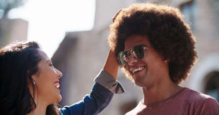 woman touching mans hair smiling.Woman strokes mans head in old town. Backlit warm light.の写真素材