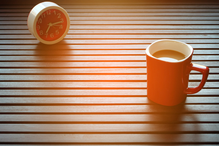 Top view a red cup of coffee is on the wooden table and this picture has a red clock, Warming Sunshine in the morning, Early morning with coffee in a red cup, space for copy or text.の写真素材