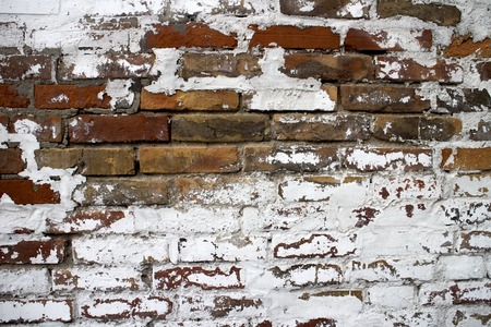 Old wall where cracked plaster and visible red brickの写真素材