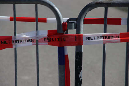 Red and white barrier tape of the Dutch police on a barrier at a crime scene
