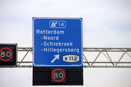 Direction sign in blue and white heading Rotterdam Noord, Schiebroek and Hilligersber S112 on motorway A20 with speed limitsのeditorial素材