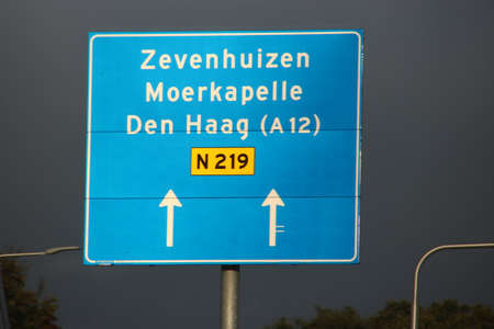 Direction sign in blue and white heading Zevenhuizen, Moerkapelle and Den Haag on N219 roadのeditorial素材