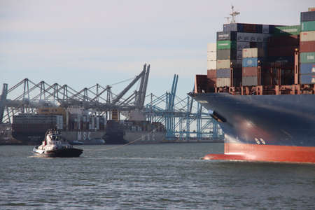 Tugship brings APL Merlion container ship inside the port of Rotterdam at the Maasvlakte Harborのeditorial素材