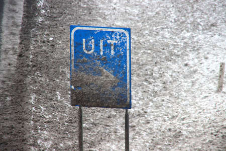 Snow on a exit sign colored by road salt at motorway A20 in the Netherlandsの写真素材