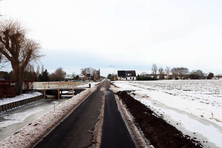 Snow on the meadows and roads in the Zuidplaspolder in the Netherlands with frozen ditchesの写真素材