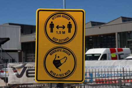 Warning sign for distance and face mask at tram stop in Utrecht the Netherlandsのeditorial素材