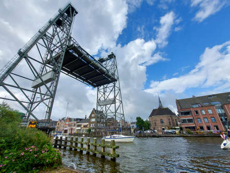 sailboat with fixed long mast passing the steel lift bridge over the Gouwe in Boskoop in South Holland in the Netherlandsのeditorial素材