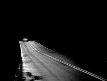 Car driving after dark on a lonely road.の写真素材