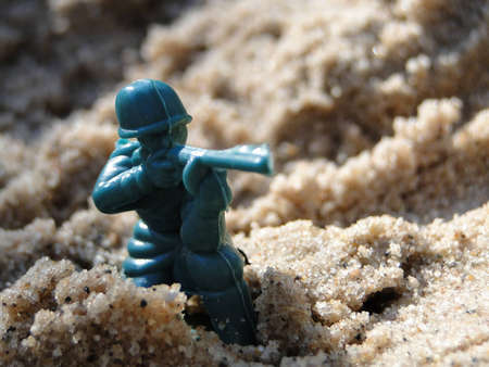 Toy green soldier in the sand box.
