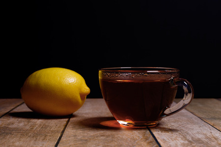 cup of fragrant black tea and juicy lemon on a black backgroundの写真素材