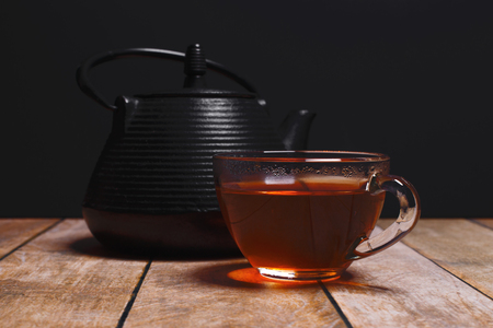 cup of fragrant black tea and teapot on a black backgroundの写真素材