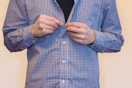 Young man trying on blue shirt and golden tie in fitting room on white background isolatedの写真素材