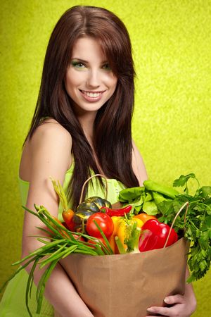 woman holding a grocery bag full of fresh and healthy food isolated on white backgroundの写真素材