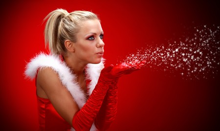 Attracive sexy girl in santa cloth blowing snow from hands.の写真素材